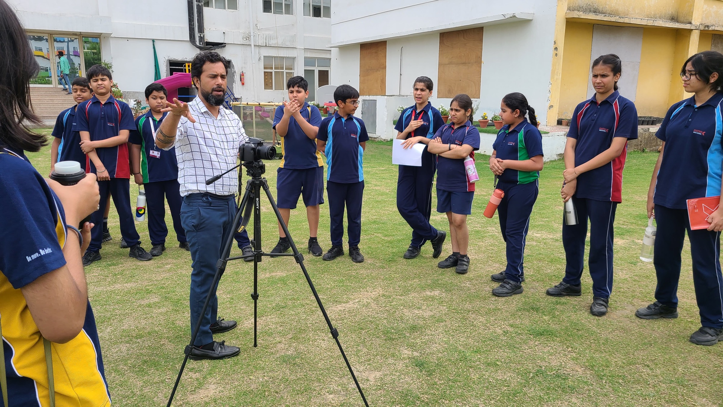 Students gathered around a camera on a tripod for an outdoor photography club session