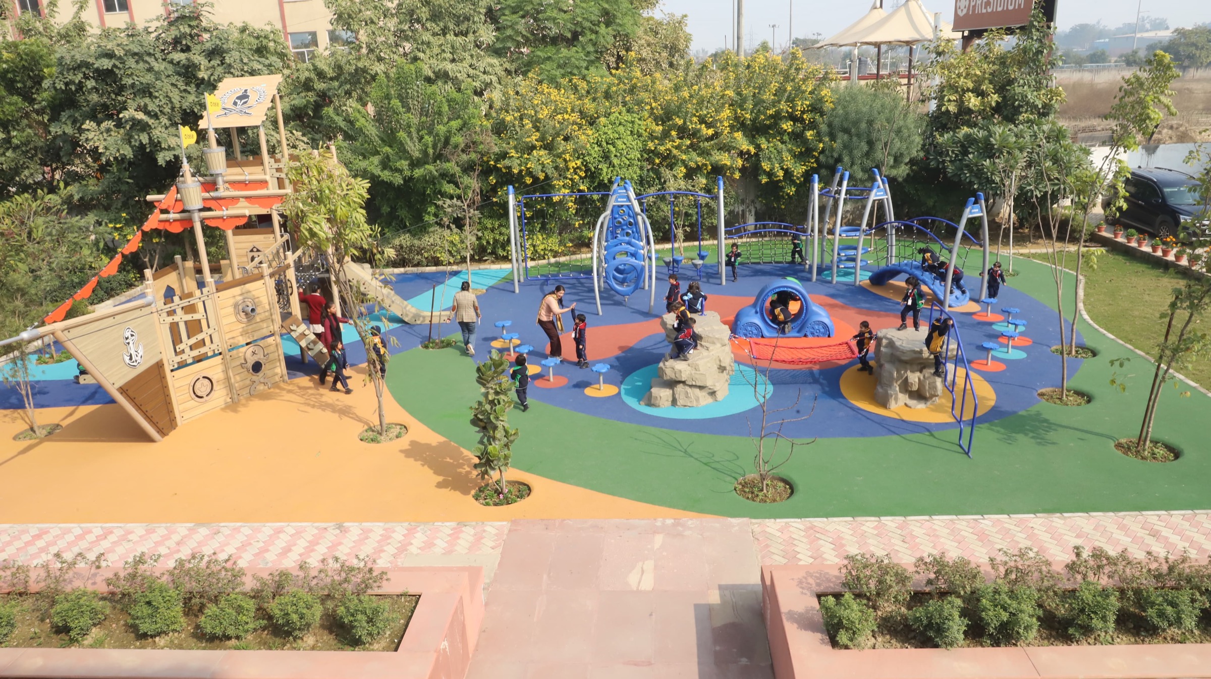 Children playing in the outdoor play area at Khaitan World School, with the pirate-ship climbing frame and climbing structures